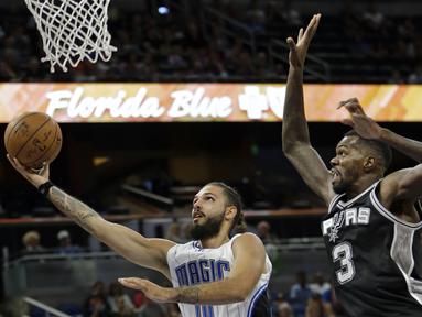 Pemain Orlando Magic, Evan Fournier (kiri) melakukan lay up saat dihadang pemain San Antonio Spurs, Dewayne Dedmon #3 pada laga NBA preseason basketball di Orlando. (AP/John Raoux)