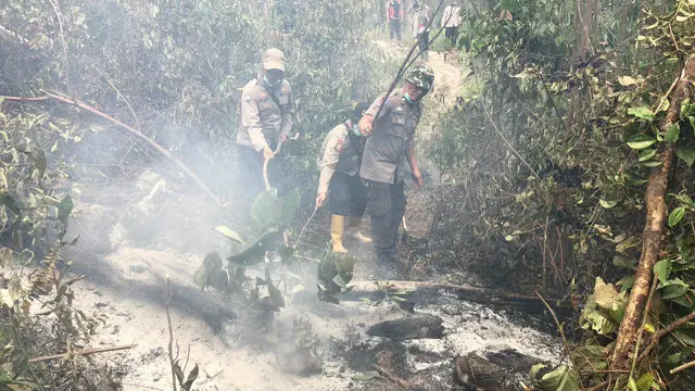 Polisi anggota Satgas Karhutla memadamkan api di hutan dan lahan yang terbakar.
