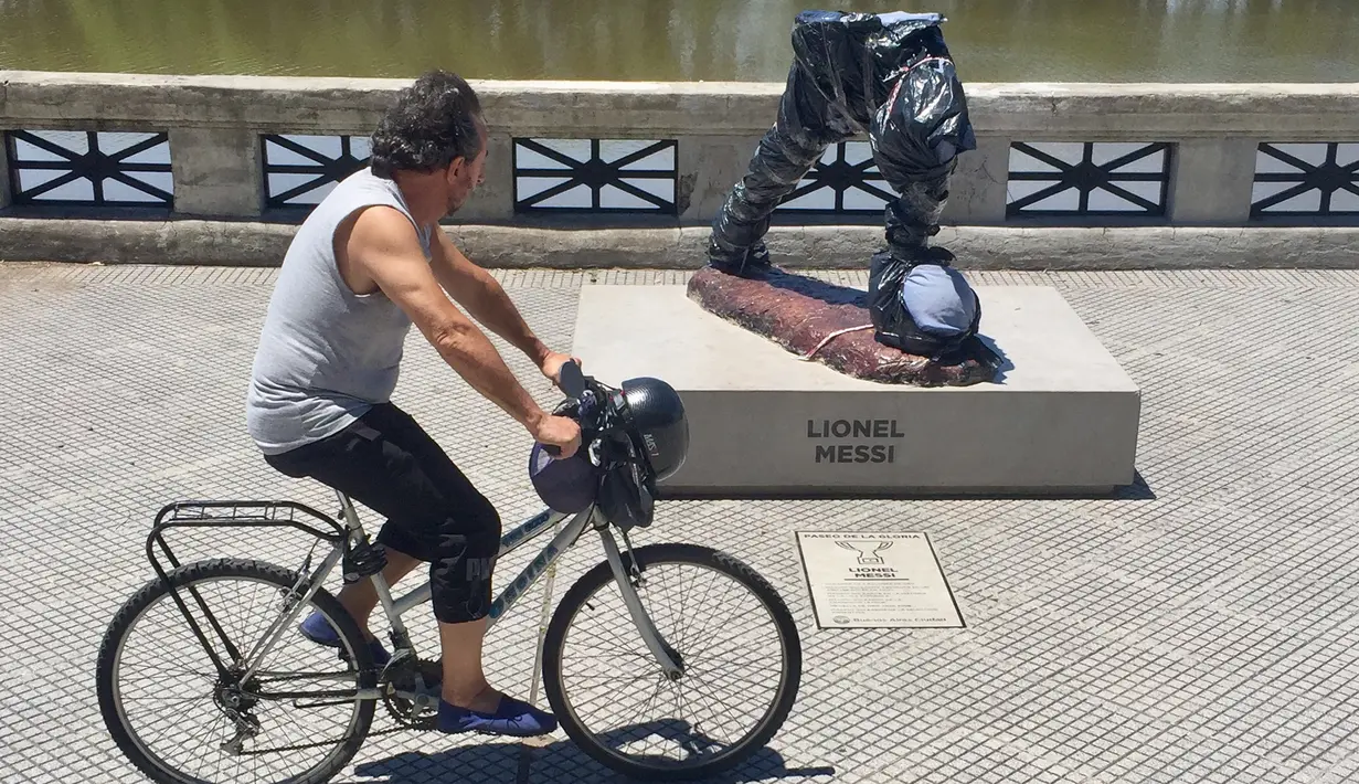 Pesepeda melintas di depan patung bintang Barcelona dan Argentina, Lionel Messi di Buenos Aires yang dirusak, Selasa (10/1). Oknum vandalisme memenggal patung ini di bagian tengah dan mengambil bagian kepala, tangan hingga badan. (AFP PHOTO/Leo RAMIREZ)
