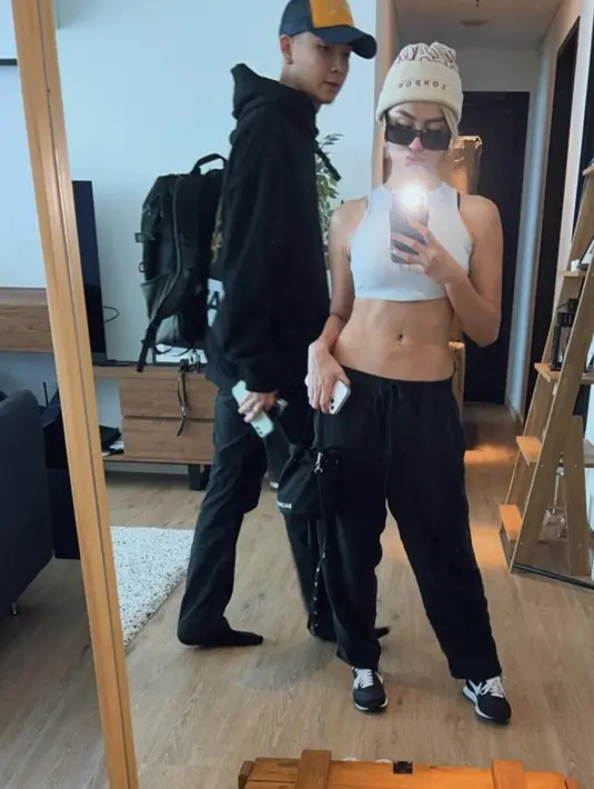 Selain hitam, ia pun pamer otot perut mengenakan tanktop putihnya. Dipadukan celana hitam dan sneakers Nikenya. Melengkapi penampilan dengan beanie hat dan kacamata hitamnya. (@agnezmo)