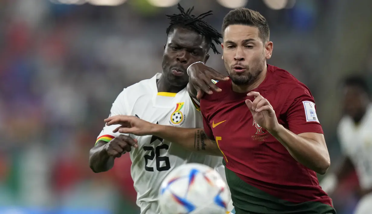 Bek Ghana Alidu Seidu  berebut bola dengan bek Portugal Raphael Guerreiro pada duel grup H Piala Dunia 2022 di stadion 974, Kamis (24/11/2022).  Portugal berhasil memimpin klasemen grup H usai kemenangan 3-2 atas Ghana.  (AP Photo/Darko Bandic)