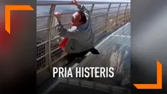 Seorang pria tampak ketakutan saat berada di atas jembatan kaca. Ia tak mampu berdiri dan berteriak histeris meminta pertolongan. Aksinya itu mengundang tawa orang-orang di sekitarnya.