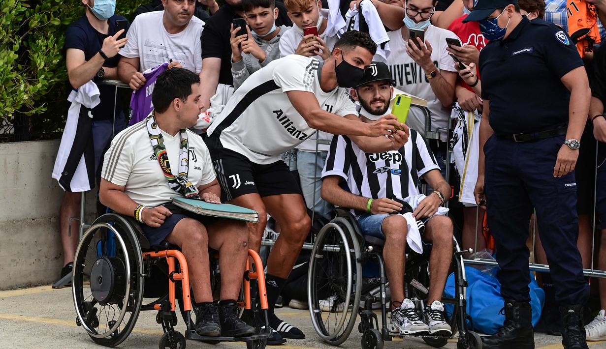 Dalam kesempatan tersebut, Cristiano Ronaldo menyempatkan waktunya untuk menyapa penggemar yang sudah menunggu diluar. dan tanpa diduga dirinya menghampiri penggemarnya yang duduk di kursi roda dan melakukan swafoto bersama. (Foto: AFP/Miguel Medina)