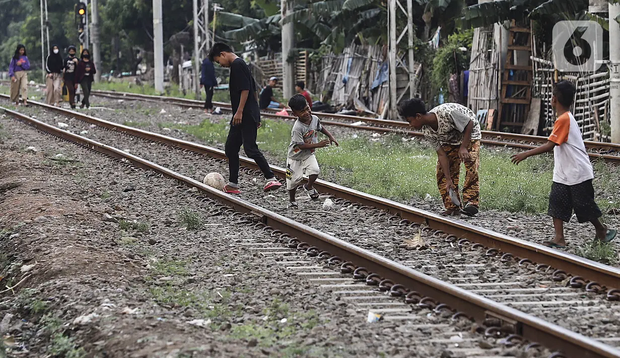 Anak-anak bermain bola di tengah perlintasan kereta api kawasan Ancol, Jakarta Utara, Kamis (19/5/2022). Data Kementerian Kesehatan pada 17 Mei 2022 mengungkapkan, enam orang meninggal karena diduga terjangkit hepatitis akut yang belum diketahui penyebabnya alias hepatitis misterius. (Liputan6.com/Johan Tallo)