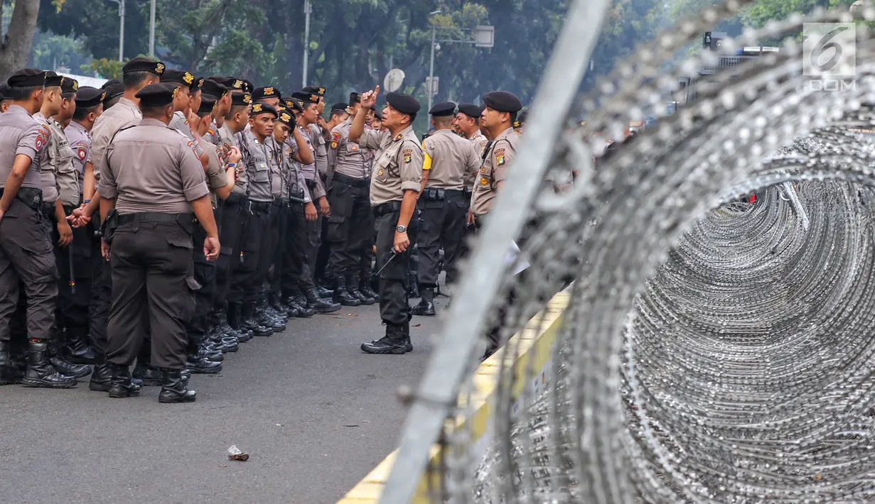 Polisi berjaga menjelang sidang perdana MK Pemilu 2019 di halaman depan Gedung Mahkamah Konstitusi, Jakarta, Jumat, (14/6/2019). Sekitar 30 ribu pesonil gabungan diterjunkan untuk mengawal jalannya sidang dengan menerapkan skema pengamanan empat lapis. (Liputan6.com/Johan Tallo)