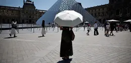Seseorang berlindung di bawah payung di depan museum Louvre di Paris saat gelombang panas yang memecahkan rekor melanda sebagian besar Eropa Barat pada Kamis 28 Mei 2026. (SIMON WOHLFAHRT/AFP)