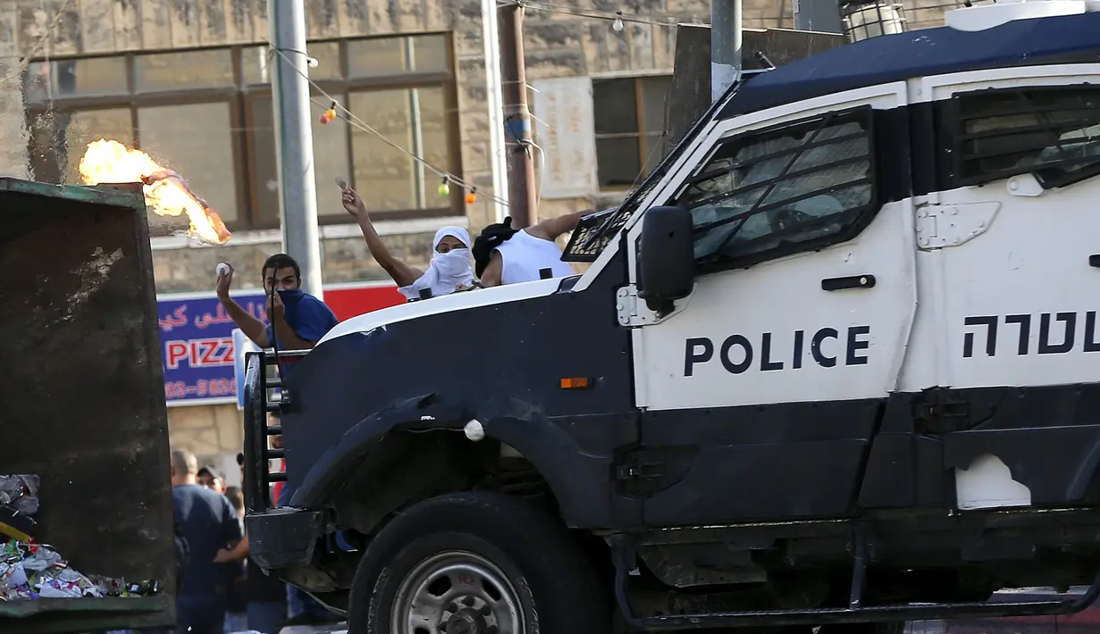 Warga Palestina melempar batu ke arah polisi Israel dalam bentrokan di Shuafat, sebuah daerah pinggiran Arab, Yerusalem, Senin (5/10/2015). Seorang remaja Palestina tewas pada Senin dalam bentrokan di Tepi Barat. (REUTERS/Ammar Awad)