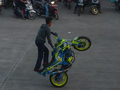 Seorang bikers melakukan aksi freestyle dengan motor di kawasan Kanal Banjir Timur, Jakarta, Selasa (29/5).Sekelompok pemuda di kawasan itu memanfaatkan waktu menunggu berbuka dengan melakukan atraksi freestyle yang mendebarkan. (Merdeka.com/Imam Buhori)