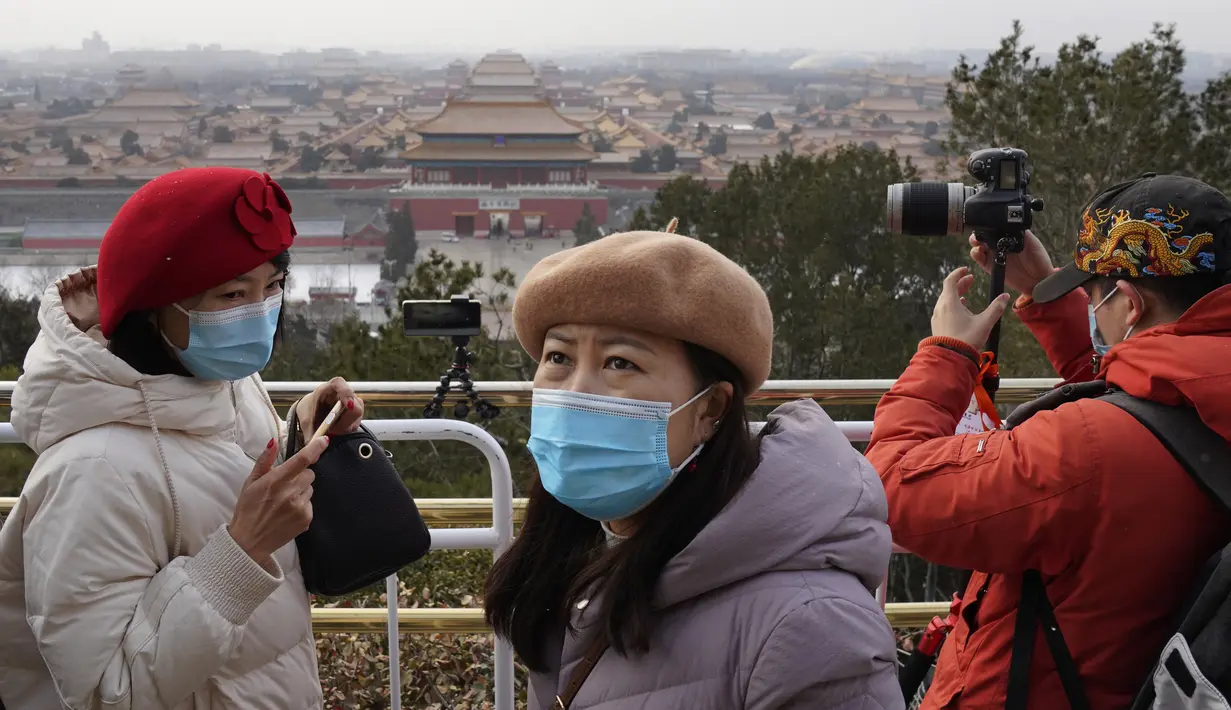 Pengunjung menikmati pemandangan menghadap Kota Terlarang dari taman Jingshan pada hari bersalju di Beijing, China, Selasa (19/1/2021). China sekarang berurusan dengan pandemi virus corona di timur lautnya yang dingin, mendorong penguncian ketat dan pembatasan perjalanan. (AP Photo/Ng Han Guan)