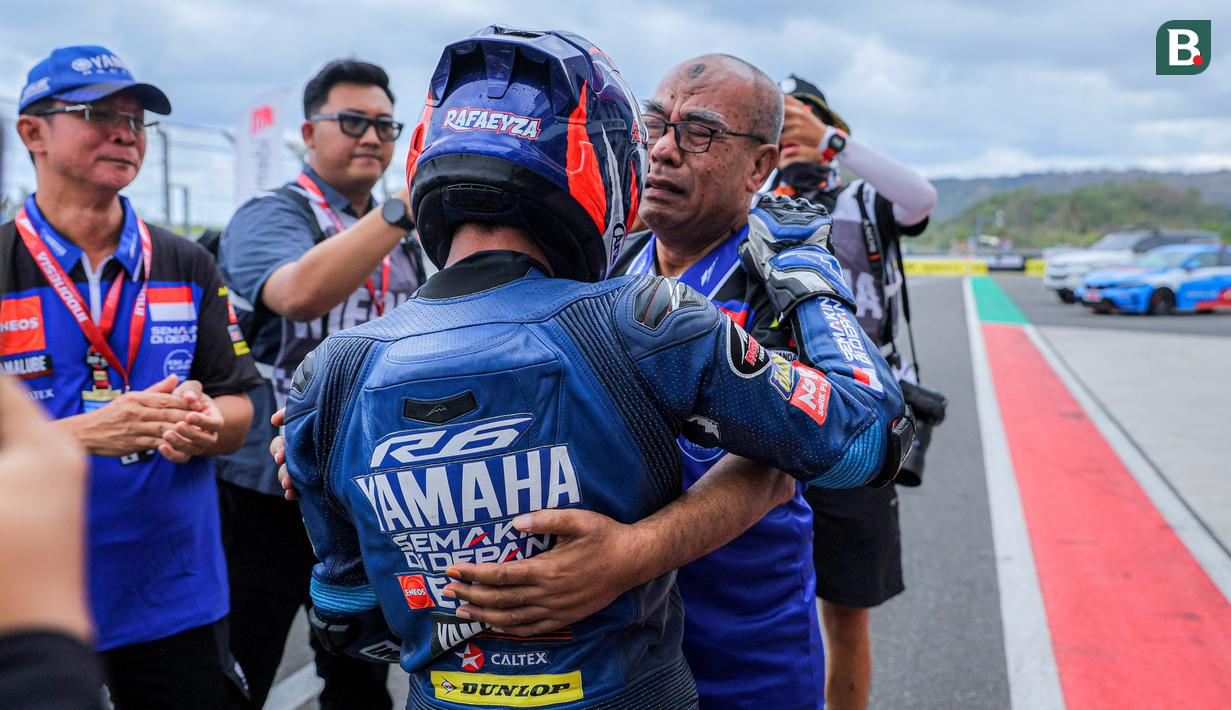 <p>Pembalap Yamaha Racing Indonesia, Muhammad Faerozi Toreqottullah melakukan selebrasi bersama ayahnya setelah finis ketiga dalam Race 1 SS600 Asia Road Racing Championship (ARRC) Mandalika 2025 di Sirkuit Internasional Mandalika, Lombok, Nusa Tenggara Barat, Sabtu (30/08/2025). (Bola.com/Bagaskara Lazuardi)</p>