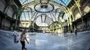Orang-orang  berseluncur di arena ice skating di bawah kubah kaca mewah legendaris, Grand Palais, Paris, Senin (17/12). Arena ice skating musiman ini terbuka untuk umum selama liburan Natal. (STEPHANE DE SAKUTIN / AFP)