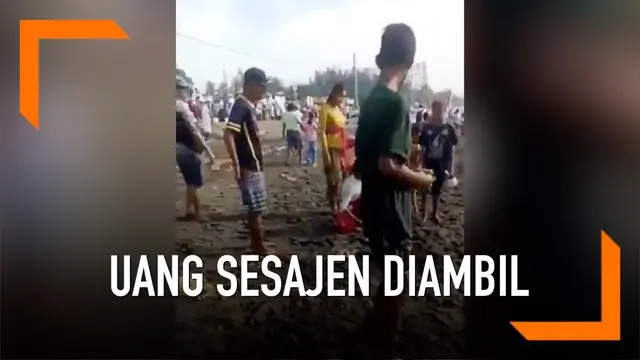 Beberapa pria terekam kamera dengan cepatnya berebut sesari atau uang yang diletakkan di sesajen saat upacara melasti di Bali.