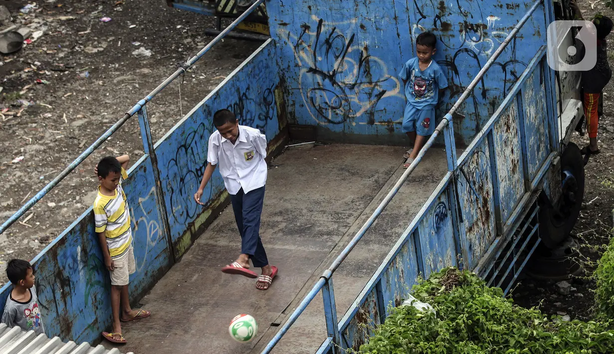 Sejumlah anak bermain sepak bola dalam bak truk di kawasan Cengkareng, Jakarta, Rabu (23/2/2022). Minimnya lahan bermain di kawasan tersebut membuat anak-anak memanfaatkan tempat yang bukan semestinya untuk bermain bola. (Liputan6.com/Johan Tallo)