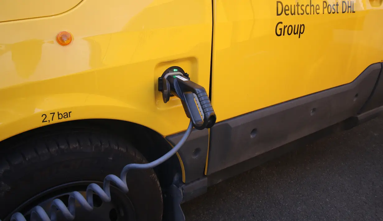 Van listrik Streetscooter mengisi daya di stasiun pengisian di kantor pos Jerman, Deutsche Post di Frankfurt am Main, 21 Juli 2018. Kantor pos Jerman mengganti armada mobil untuk mengirimkan surat dan paket dengan mobil van listrik. (Yann Schreiber/AFP)