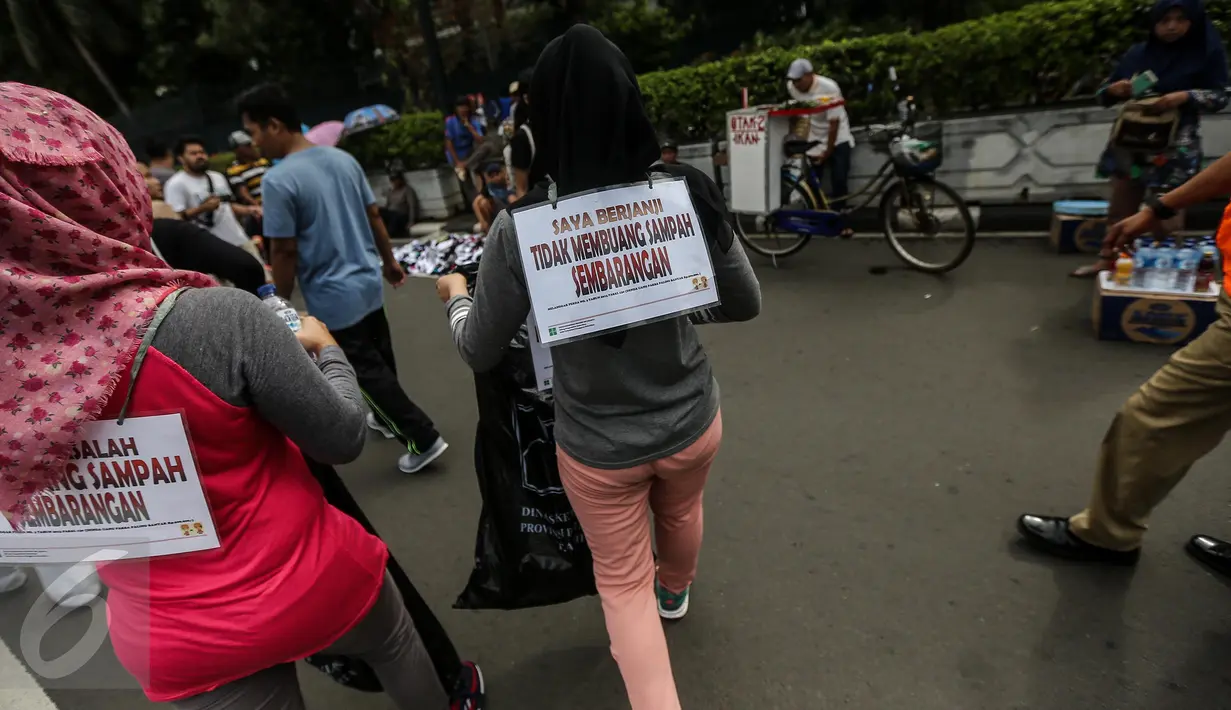 Pengunjung car free day (CFD) dikenakan sanksi memunguti sampah di kawasan Bundaran HI, Jakarta, Minggu (29/1). Mereka terjaring operasi tangkap tangan (OTT) karena membuang sampah sembarang di arena CFD. (Liputan6.com/Faizal Fanani)
