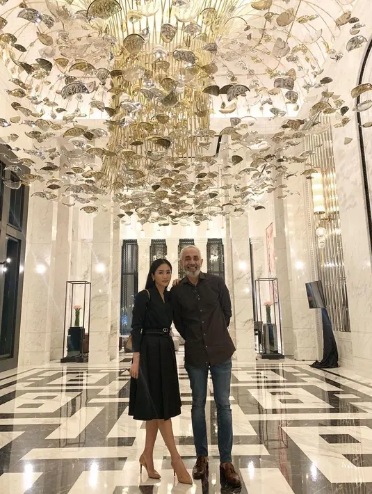 Berpose dengan sang suami, di sini Bunga Zainal tampil mengenakan midi pleated dress dengan lengan panjang berwarna hitam. Tampilan yang sudah membuatnya terlihat cantik ini hanya ditambahkan belt kecil dari brand Dior dan tas berwarna kuning dari brand Chanel. Foto: Instagram.