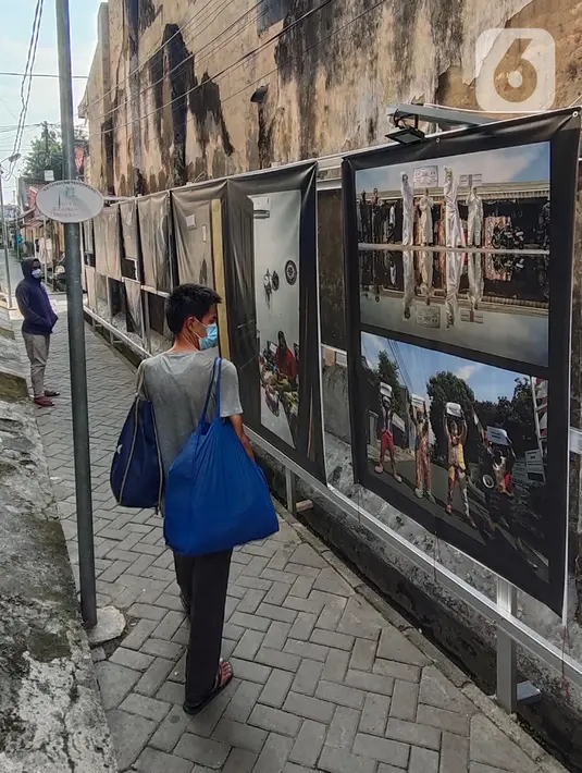 Warga melihat pameran foto jurnalistik karya pewarta foto Indonesia Tangerang di kawasan Pasar Lama, Tangerang, Minggu (30/5/2021).  Pameran foto ini juga mengingatkan masyarakat terus menjaga protokol kesehatan untuk indonesia yang sehat. (Liputan6.com/Angga Yuniar)