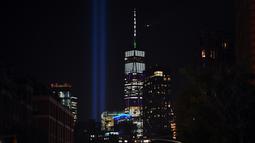 'Tribute in Light'  dinyalakan untuk memperingati serangan gedung kembar WTC yang terlihat di dekat gedung One World Trade Center, New York City, Selasa (10/9/2019). Cahaya kembar itu jadi simbol menara kembar WTC yang hancur diserang kelompok pembajak pesawat 18 tahun silam. (Johannes EISELE/AFP)