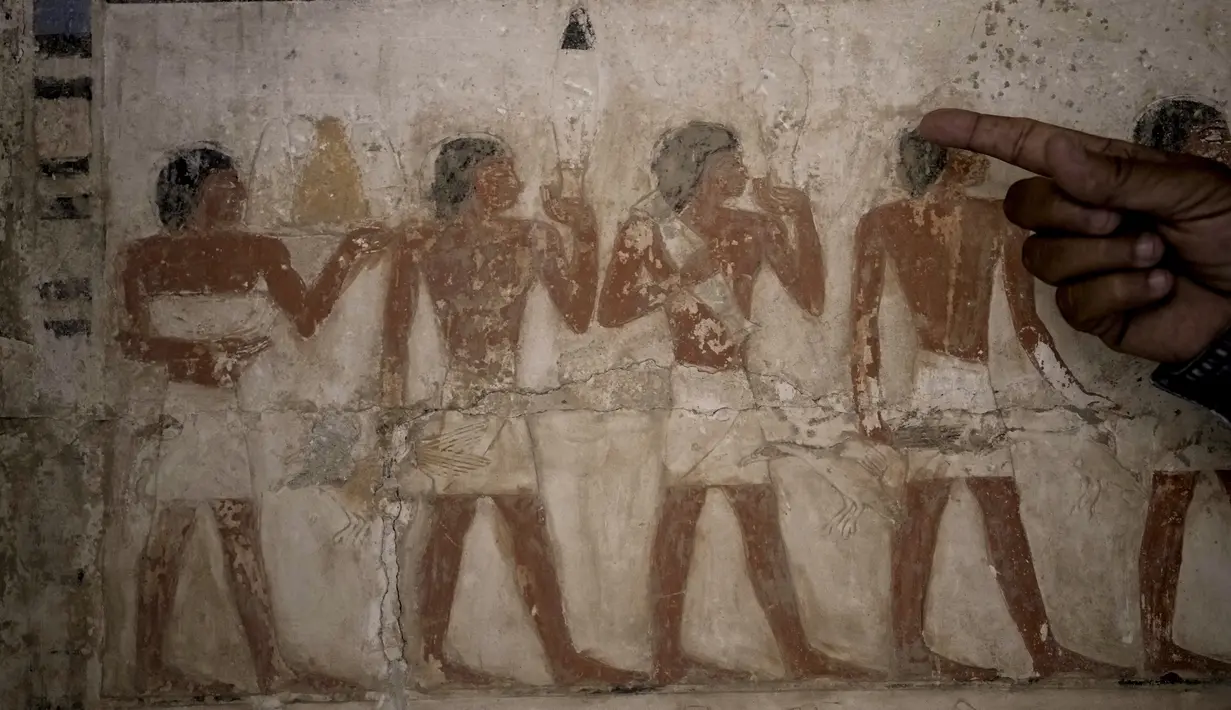 Seorang arkeolog Mesir menunjuk ke sebuah lukisan berwarna yang menunjukkan persembahan korban di sebuah makam yang baru-baru ini ditemukan yang dikatakan milik seorang pejabat tinggi Dinasti kelima bernama "Ne Hesut Ba" (2400 SM), di situs Step Pyramid of Djoser di Saqqara, 24 kilometer (15 mil) barat daya Kairo, Sabtu, 27 Mei 2023. (AP Photo/Amr Nabil)