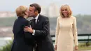 Presiden Prancis Emmanuel Macron (tengah) mencium Kanselir Jerman Angela Merkel (kiri) disaksikan istrinya Brigitte Macron (kanan) yang di KTT G7, Biarritz, Prancis, Sabtu (24/8/2019). KTT G7 beragenda pertahanan demokrasi, kesetaraan jender, pendidikan, dan lingkungan. (AP Photo/Markus Schreiber)
