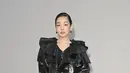 Kim Min-ha menghadirkan interpretasi paling avant-garde dengan jaket bergaya trench berbahan metalik hitam bermotif kotak-kotak. Lengkap detail kerah berlapis oversized yang dramatis, dipadukan celana kulit hitam dan tas selempang hitam. [dok. Burberry]