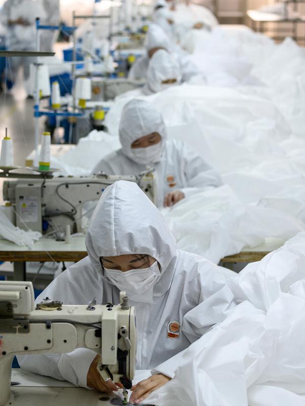 Para pekerja menjahit bahan untuk digunakan membuat pakaian antivirus di pabrik garmen Zhejiang Ugly Duck Industry, di Wenzhou, 28 Februari 2020. Wabah virus corona di China membuat produsen pakaian itu mulai memproduksi baju hazmat yang banyak diburu orang untuk melindungi dirinya. (NOEL CELIS/AFP)