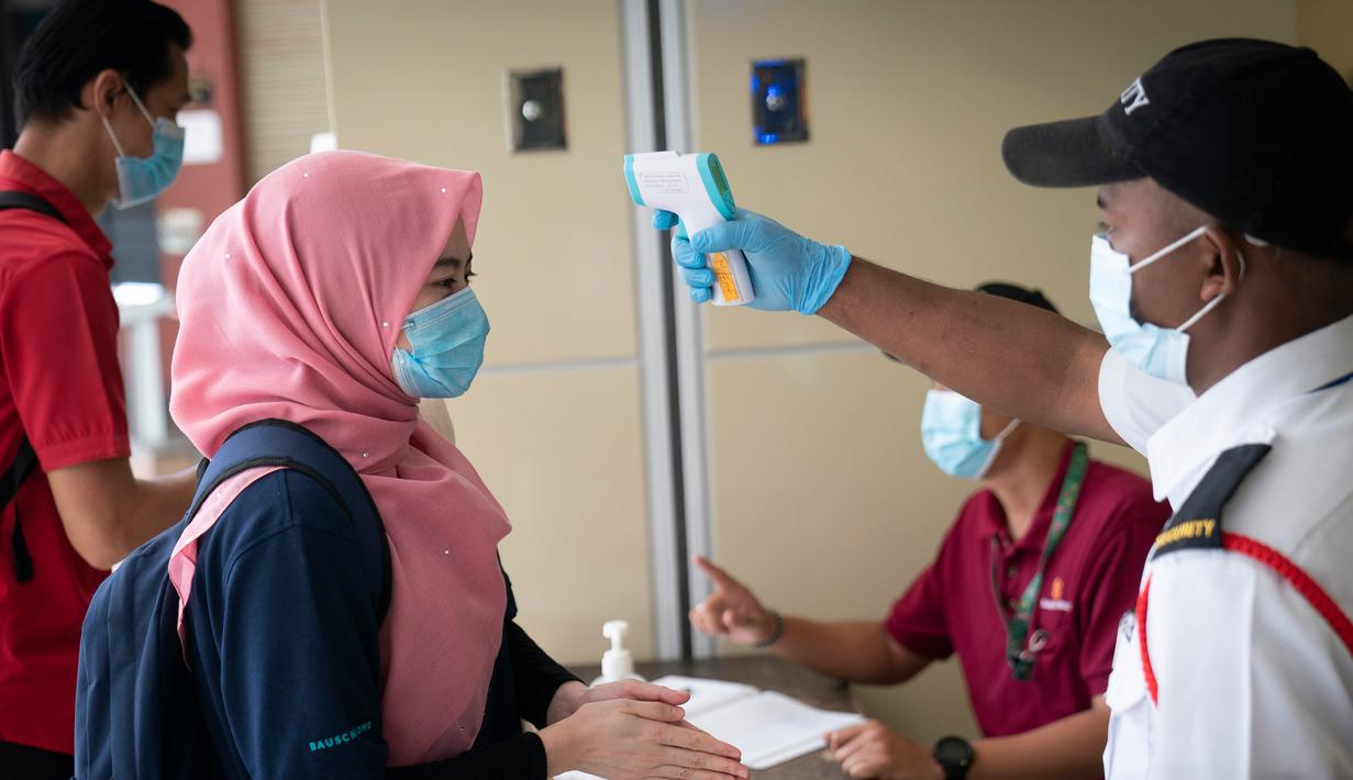 Seorang wanita diperiksa suhu tubuhnya oleh seorang petugas keamanan di pintu masuk pusat perbelanjaan di Kuala Lumpur, Malaysia, Senin, (4/5/2020). (AP/Vincent Thian)