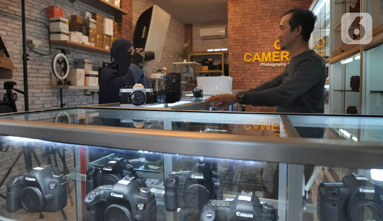 Calon pembeli mencoba kamera bekas  yang dijual belikan di CSZ Camera di kawasan Pondok jagung, Tangerang Selatan, Banten, Senin (20/12/2021). Peningkatan penjualan didorong karena kebutuhan memotret untuk komunitas dan media visual penjualan online. (merdeka.com/Arie Basuki)
