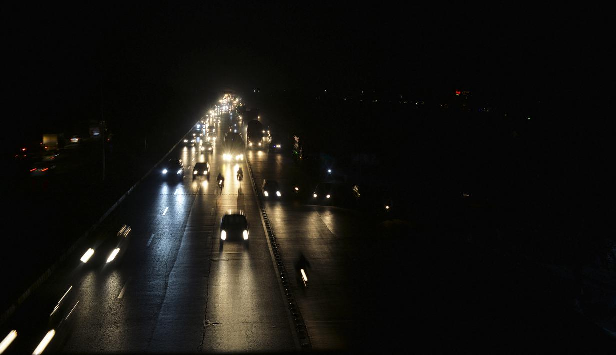 Komuter berjalan di sepanjang jalan selama pemadaman listrik nasional, di Islamabad, Pakistan pada 23 Januari 2023. Pemadaman kali ini menjadi pemadaman listrik terluas yang pernah tercatat di Pakistan sejak 2021 lalu. (Farooq NAEEM / AFP)