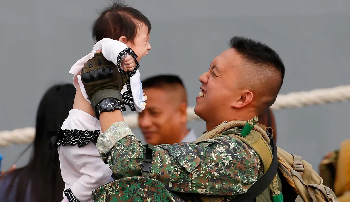 Ekspresi tentara Filipina saat mengendong anaknya anaknya setelah bertempur di kota Marawi melawan para militan di Manila, Filipina (30/10). Kota Marawi berhasil direbut dari para militan. (AP Photo / Bullit Marquez)