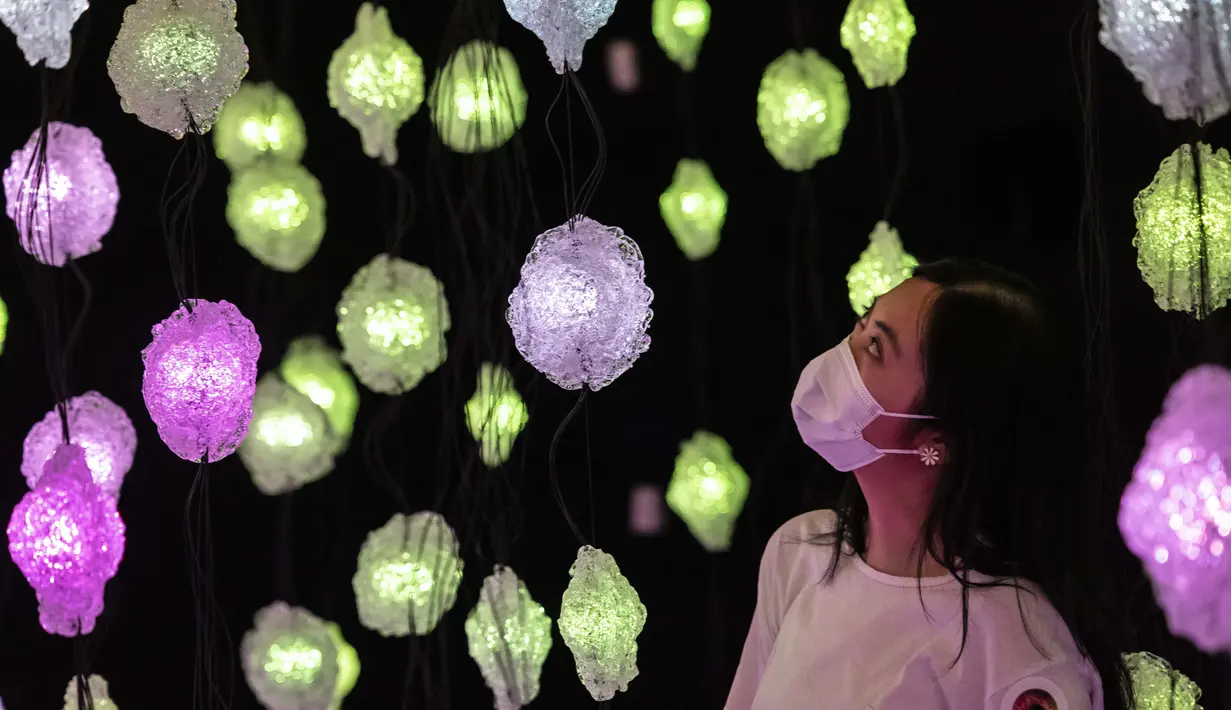 Seorang wanita melihat "Pixel Forest" oleh seniman Swiss Pipilotti Rist, sebuah instalasi seni dari 3000 lampu LED pahatan tangan yang digantung di langit-langit di Tai Kwun di Hong Kong (18/8/2022). (AFP/Isaac Lawrence)