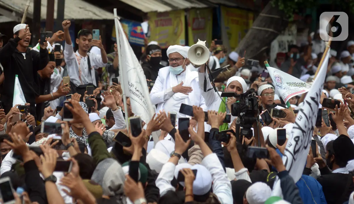 Rizieq Shihab menyapa massa pendukungnya saat tiba di kediamannya di Jalan Petamburan, Jakarta, Selasa (10/11/2020). Rizieq Shihab tiba di kediamannya usai pulang dari Arab Saudi. (merdeka.com/Imam Buhori)