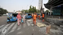 Petugas PPSU melakukan penambalan pada jalan yang berlubang di wilayah Senen, Jakarta, Selasa (26/7). Penambalan jalan berlubang ini bertujuan untuk kenyamanan pengguna jalan yang melintas. (Liputan6.com/Yoppy Renato)
