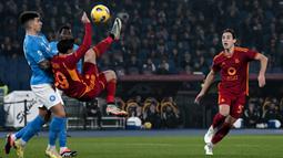 Striker AS Roma, Nicola Zalewski (tengah) berusaha melepaskan tendangan akrobatik di depan bek Napoli, Giovanni di Lorenzo pada laga pekan ke-17 Liga Italia 2023/2024 di Olympic Stadium, Roma, Minggu (24/12/2023) dini hari WIB. (AFP/Tiziana Fabi)