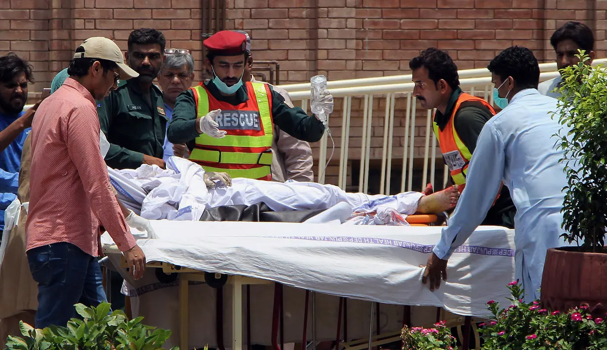 Petugas penyelamat dan staf rumah sakit Pakistan mengevakuasi korban ledakan truk tangki minyak di rumah sakit di Multan, Pakistan (25/6). Akibat insiden ini, sedikitnya 123 orang tewas dan 100 lainnya mengalami luka-luka.  (AP Photo / Adeel Khan)