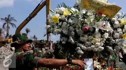 Anggota TNI mengatur Karangan bunga yang datang di lokasi jatuhnya pesawat hercules C 130 di jalan jamin ginting, Medan, Kamis (2/7/2015). Karangan bunga sebagai simbol duka cita atas peristiwa yang merenggut ratusan nyawa. (Liputan6.com/Johan Tallo)
