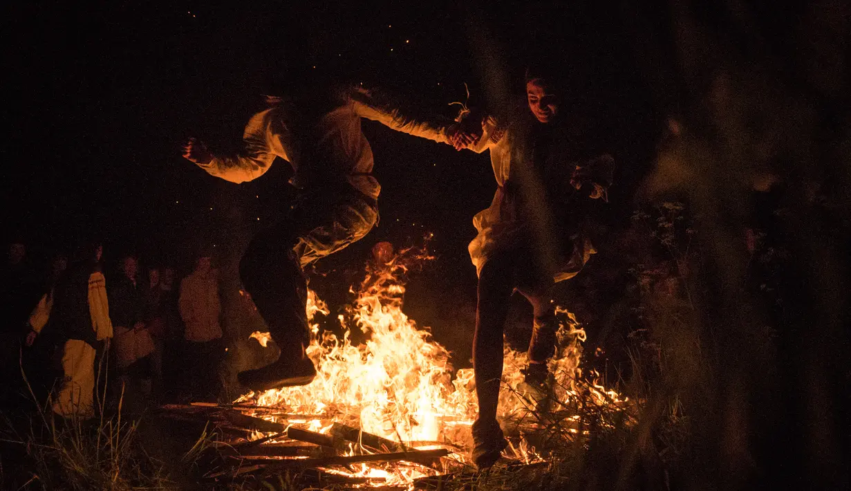 Peserta ritual melompat diatas api unggun saat mengikuti upacara ritual pagan kuno di dekat desa Glubokovo, Rusia (24/6). (AFP Photo/Andrei Borodulin)