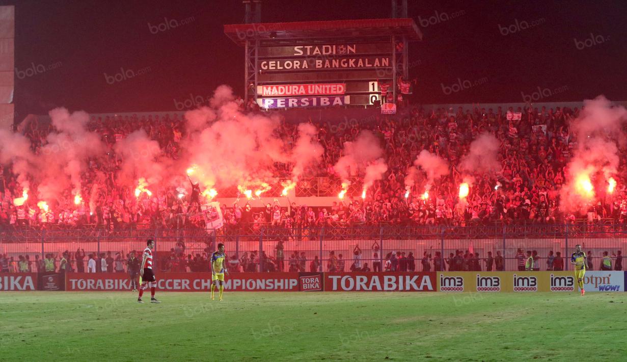 Suporter Madura United, menyalakan flare memperingati ulang tahunnya membuat laga melawan Persiba Balikpapan tertunda pada Torabika SC 2016 di Stadion Gelora Bangkalan, Senin(13/6/2016).  (Bola.com/Nicklas Hanoatubun)