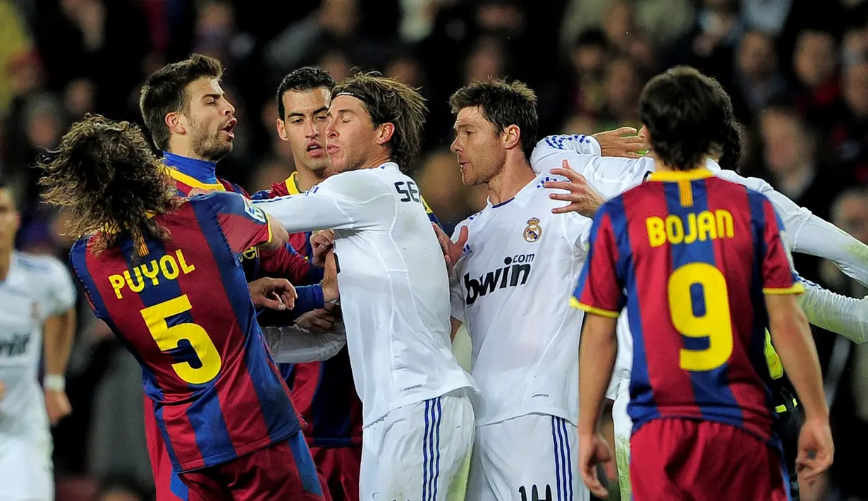 Pemain Madrid, Sergio Ramos, mendorong Carles Puyol hingga terjatuh saat Puyol memprotes Ramos karena melanggar keras Messi. Barcelona menang 5-0 dalam laga di Stadion Camp Nou, Barcelona, (29/11/2010). (AFP Photo/Josep Lago)