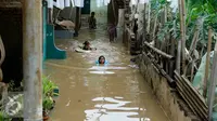 Anak-anak gang H. Maliki, Cawang memanfaatkan banjir untuk berenang, Jakarta, Senin (16/11). Pasca datangnya air kiriman dari Bogor, puluhan rumah di pinggir kali Ciliwung terendam banjir dengan ketinggian mencapai 3 meter. (Liputan6.com/Yoppy Renato)