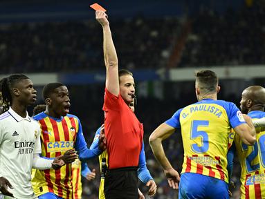 Wasit Javier Alberola Rojas memberikan kartu merah kepada pemain Valencia, Gabriel Paulista saat melawan Real Madrid pada laga Liga Spanyol di Stadion Santiago Bernabeu, (2/2/2023). Real Madrid meraih kemenangan penting pada pekan ke-17 Liga Spanyol 2022/2023. (AFP/Javier Soriano)
