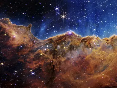 Gambar ini dirilis oleh NASA pada 12 Juli 2022, menunjukkan tepi daerah pembentuk bintang muda di dekatnya, NGC 3324 di Nebula Carina. Ditangkap dalam cahaya inframerah oleh Near-Infrared Camera (NIRCam) melalui Teleskop Luar Angkasa James Webb, gambar ini mengungkapkan area kelahiran bintang yang sebelumnya tak terlihat, menurut NASA. (NASA, ESA, CSA, and STScI via AP)