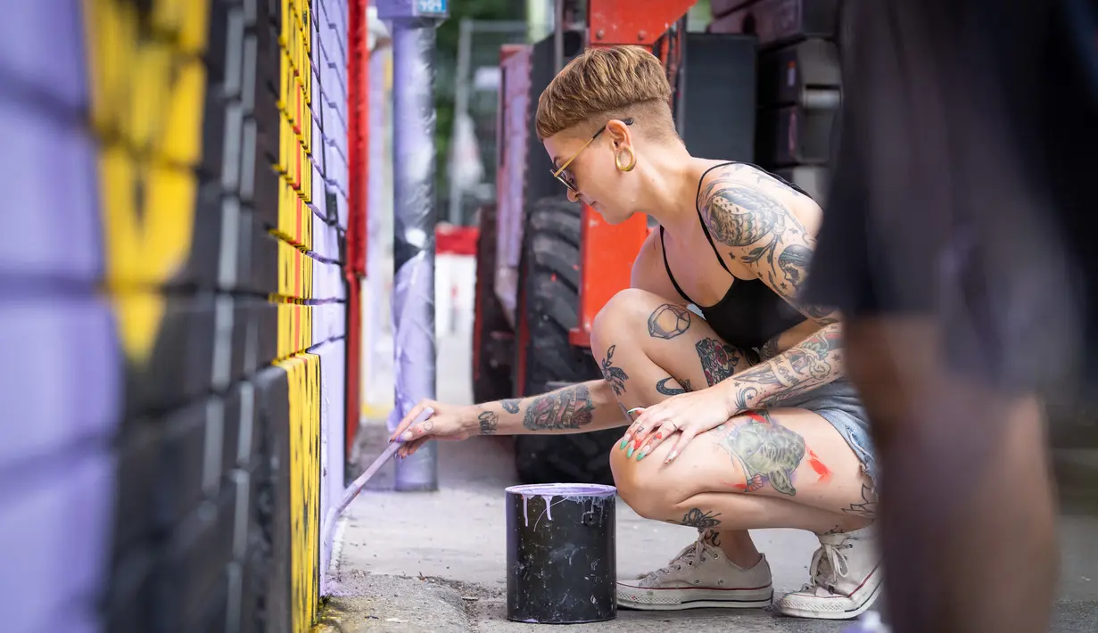 Nikki, asisten seniman Hatecopy, melukis saat Festival Mural Montreal di Quebec, Kanada, 16 Juni 2022. Sebanyak 21 seniman melukis mural baru tahun ini. (Paola Chapdelaine/AFP)