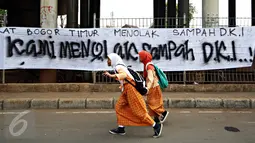 Anak melintas depan spanduk penolakan sampah DKI Jakarta di Jalan Raya Narogong, Bogor Timur, Jawa Barat, Rabu (4/11/2015). Ormas bersama warga menyatakan akan tetap menolak truk sampah yang melintas di kawasan tersebut. (Liputan6.com/Immanuel Antonius)