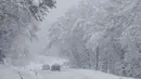 Mobil melintasi jalan yang tertutup salju di Kocevje, dekat Ljubljana Slovenia, Senin (23/1/2023). Badai salju dengan angin kencang telah menghambat lalu lintas di jalan raya utama di Slovenia pada hari Senin dan menyebabkan beberapa bagian negara tanpa listrik untuk sementara waktu. (AP Photo)
