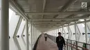 Warga melintasi jembatan penyeberangan (Skybridge) yang menghubungkan Stasiun LRT Velodrome dengan Halte Transjakarta Pemuda di Rawamangun, Jakarta, Senin (29/7/2019). Skybridge berdesain artistik tersebut memiliki panjang sekitar 500 meter dan lebar 2 meter. (Liputan6.com/Immanuel Antonius)