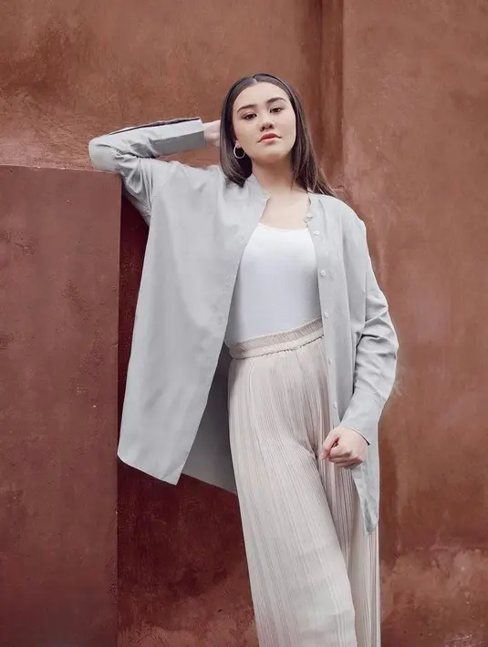 Perempuan berdarah campuran Belanda, Jawa, Madura, dan Sunda ini kini memadukan kemeja warna abu-abu, tank top, dan pleats pants warna cream. (Instagram/Aaliyah.massaid).