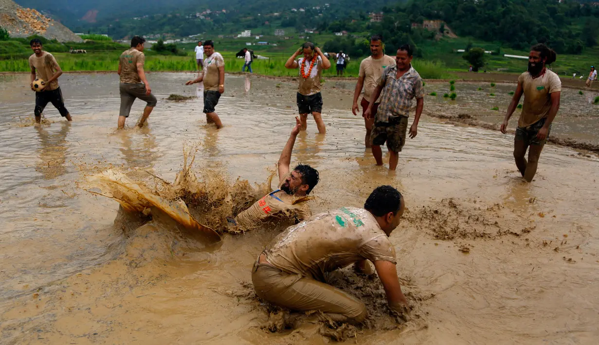 Sejumlah warga Nepal bersuka ria di lumpur pada Asar Pandra, atau hari menanam padi nasional di Lalitpur, 29 Juni 2018. Asar Pandra diadakan sebagai tanda dimulainya kembali aktivitas tanam padi di sawah saat musim hujan tiba. (AP Photo/Niranjan Shrestha)
