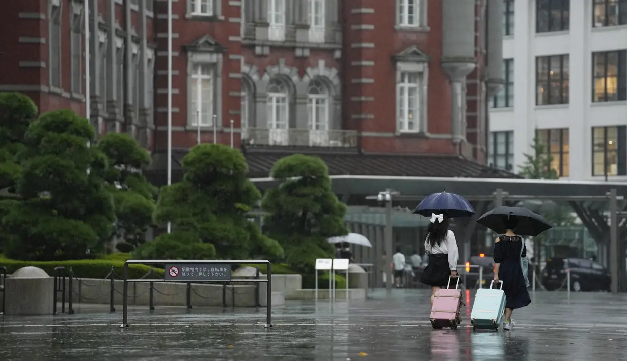 Perempuan berjalan keluar dari stasiun kereta api Tokyo di tengah hujan, Selasa (20/9/2022). Dilansir dari AP, badai merusak sebuah tembok di pusat ruang angkasa Badan Eksplorasi Luar Angkasa Jepang, di pulau Tanegashima, selatan pulau Kyushu, kata Kementerian Ekonomi dan Industri. (AP Photo/Hiro Komae)