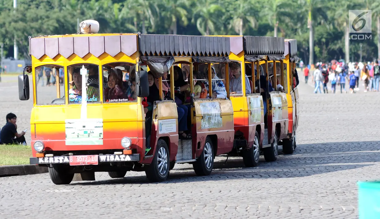 Kereta wisata membawa pengunjung mengelilingi kawasan Monumen Nasional, Jakarta, Senin (25/12). Libur perayaan Natal dimanfaatkan warga untuk berwisata di kawasan Monumen Nasional. (Liputan6.com/Helmi Fithriansyah)